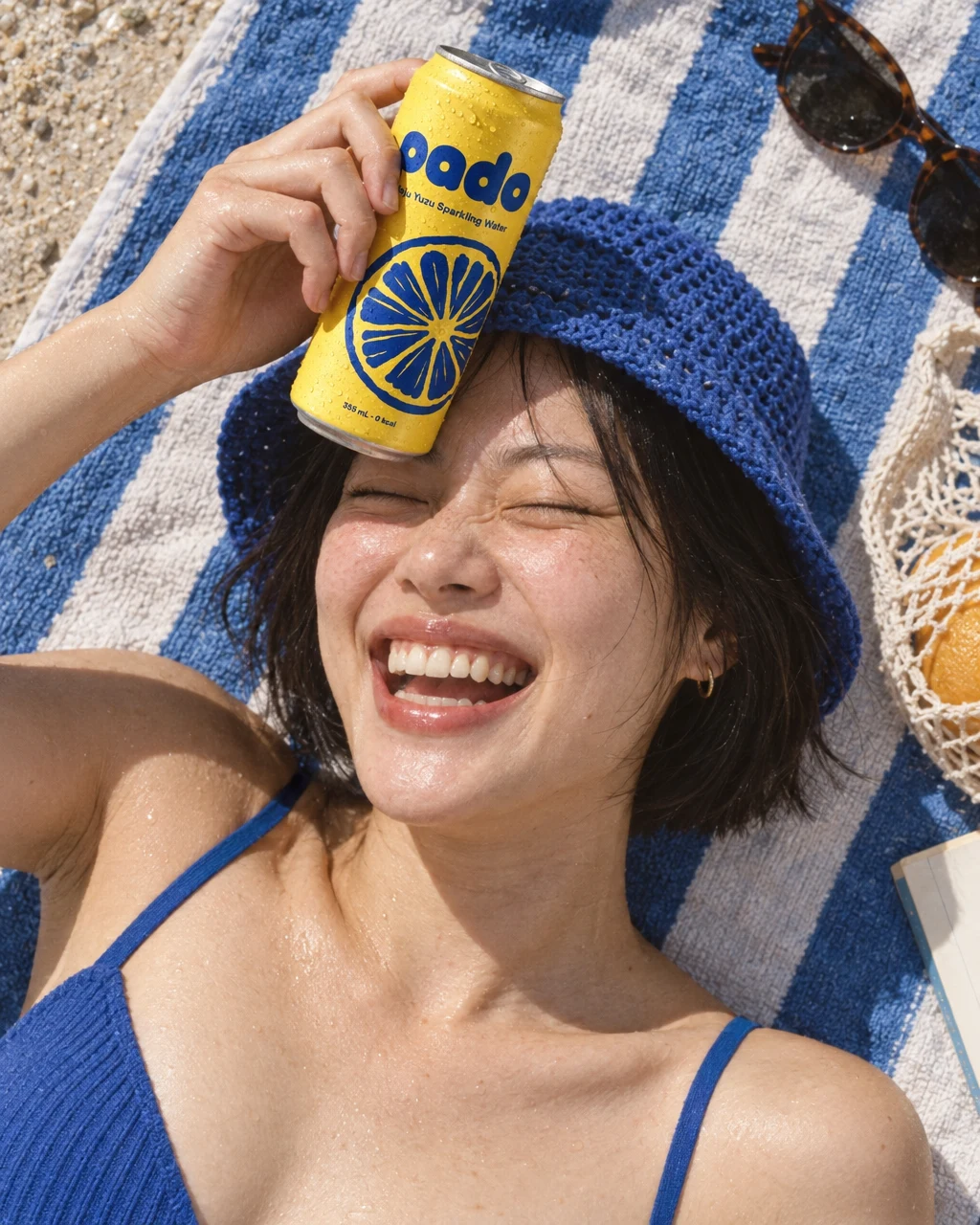 Someone laughing on a beach towel, holding a pado can