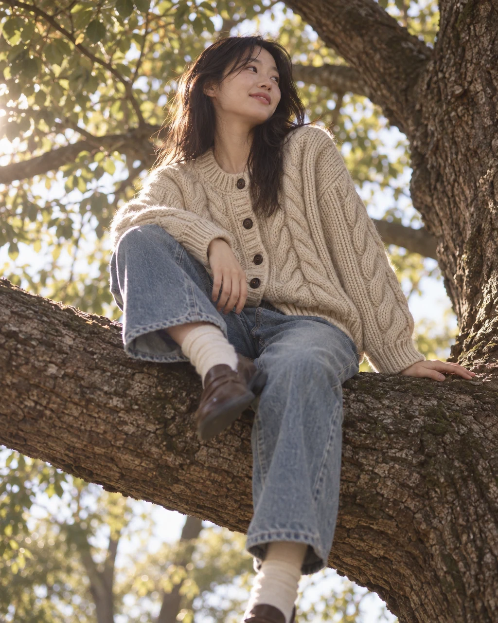 The OLLAE cable cardigan, sitting on a tree branch